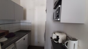 A compact kitchen with white cabinets, a built-in oven, a microwave, and a coffee maker. - Pleasant T2 excellent location near the old port secure parking, Wifi (La Rochelle)