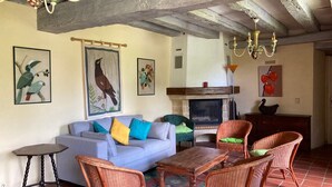 A living room with a fireplace, wicker furniture, and artwork on the walls.