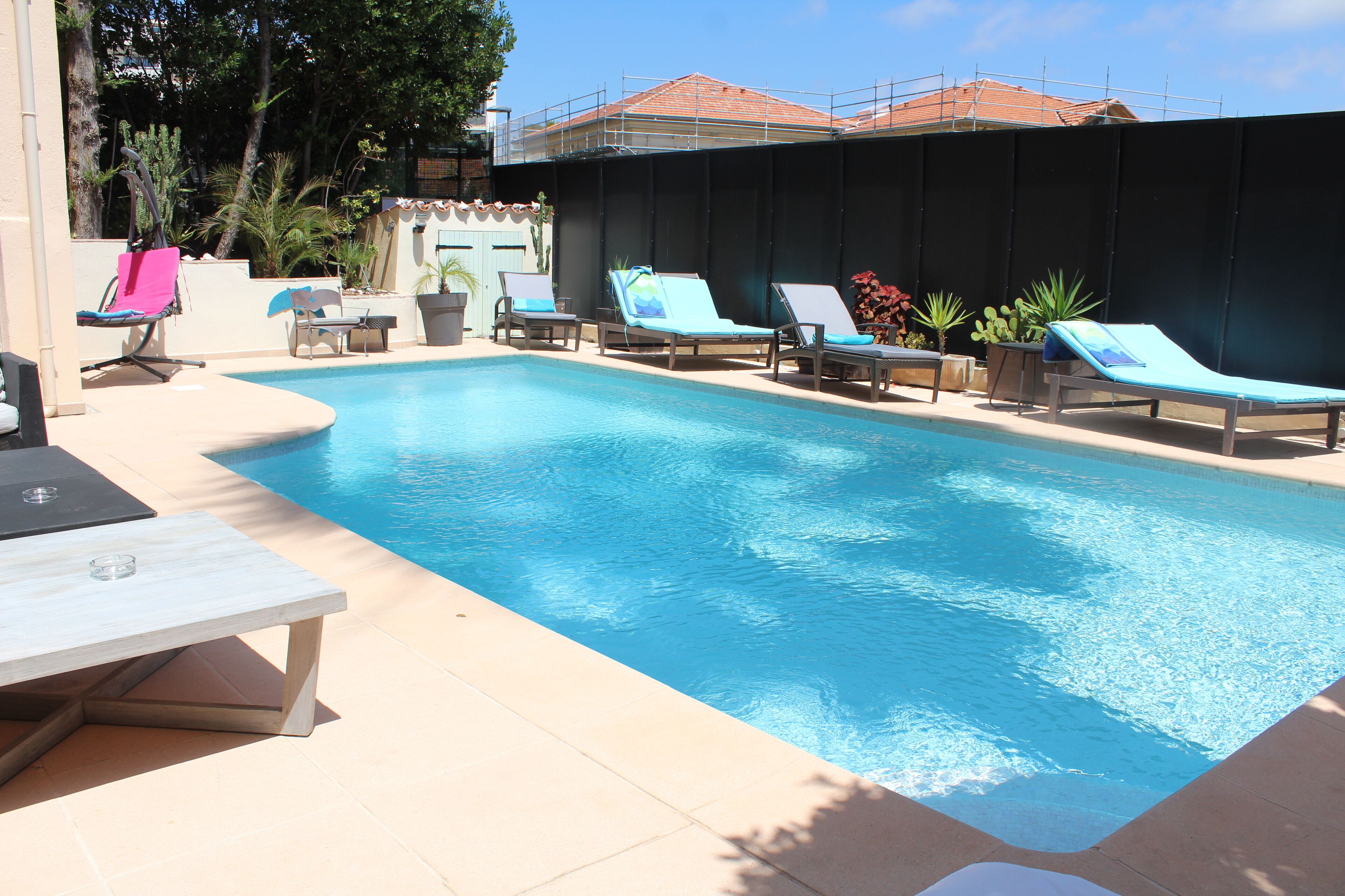 A swimming pool with lounge chairs and a table.