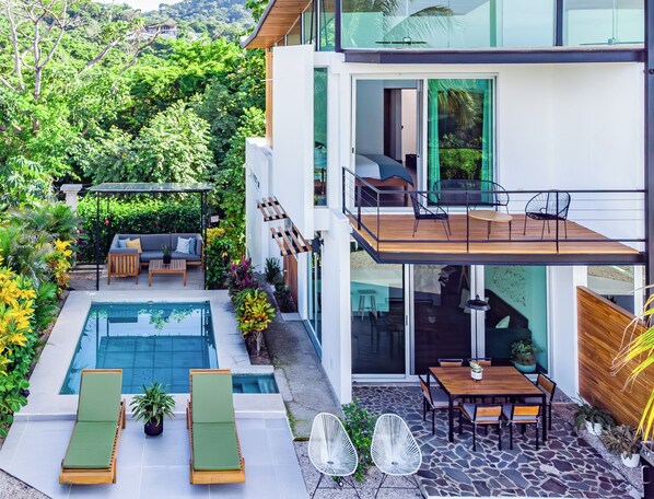 A modern two-story house with a swimming pool, outdoor seating, and a balcony.