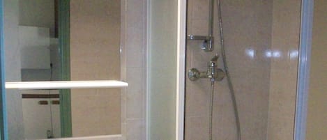 A bathroom with a white sink, a mirror, and a glass-enclosed shower area.