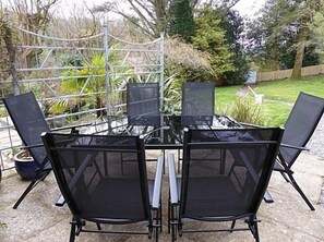 Una mesa con cubierta de vidrio y cuatro sillas negras de malla.