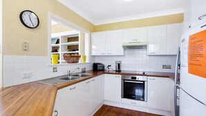 Eine Küche mit weißen Schränken, einer Holzauskładung, einem Geschirrspüler von Bosch, einem Toaster und einer Uhr an der Wand.