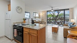 A modern kitchen with a central island, a dining area with a view, and a living room with a sofa and a table. - Quiet, comfortable and across from gorgeous Charley Young beach  (Kihei)