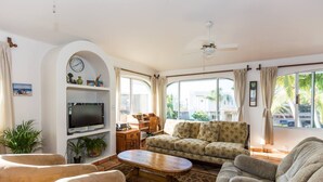 A living room with a TV, sofa, chairs, and a coffee table.