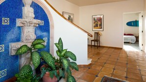 A staircase with a blue-tiled wall, a wooden handrail, and a potted plant.