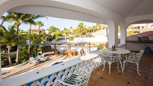 A covered outdoor area with a pool, lounge chairs, and a table with chairs.