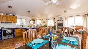 A spacious kitchen with wooden cabinets, a tiled backsplash, and a dining area with a glass table set for four.