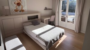 A modern bedroom with a bed, bedside table, chair, and a large window with curtains. - Charming villa, well-equipped, sleeps 4, 3 bedrooms, very quiet. (Villeneuve Les Avignon)