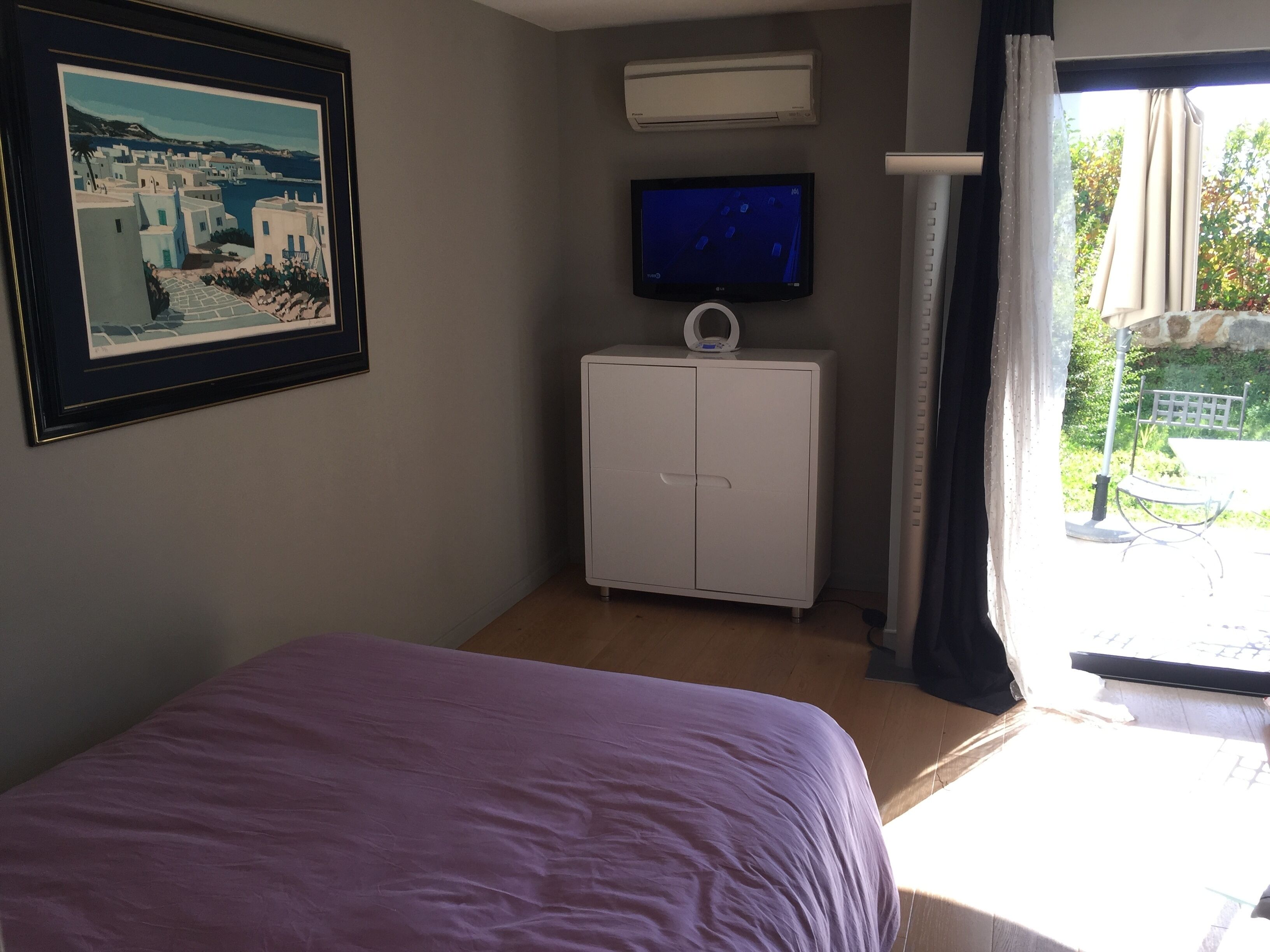 A bedroom with a bed, a TV, a wardrobe, and a window with curtains.