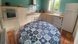 A kitchen with teal walls, a patterned tablecloth, and basic appliances. - Nice house classified 3 * Located in Dompierre Sur Mer, 5 Kms De La Rochelle (Dompierre-Sur-Mer)