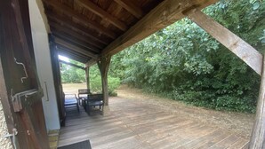 A wooden deck with a covered seating area and a view of a lush garden. - Nice house classified 3 * Located in Dompierre Sur Mer, 5 Kms De La Rochelle (Dompierre-Sur-Mer)