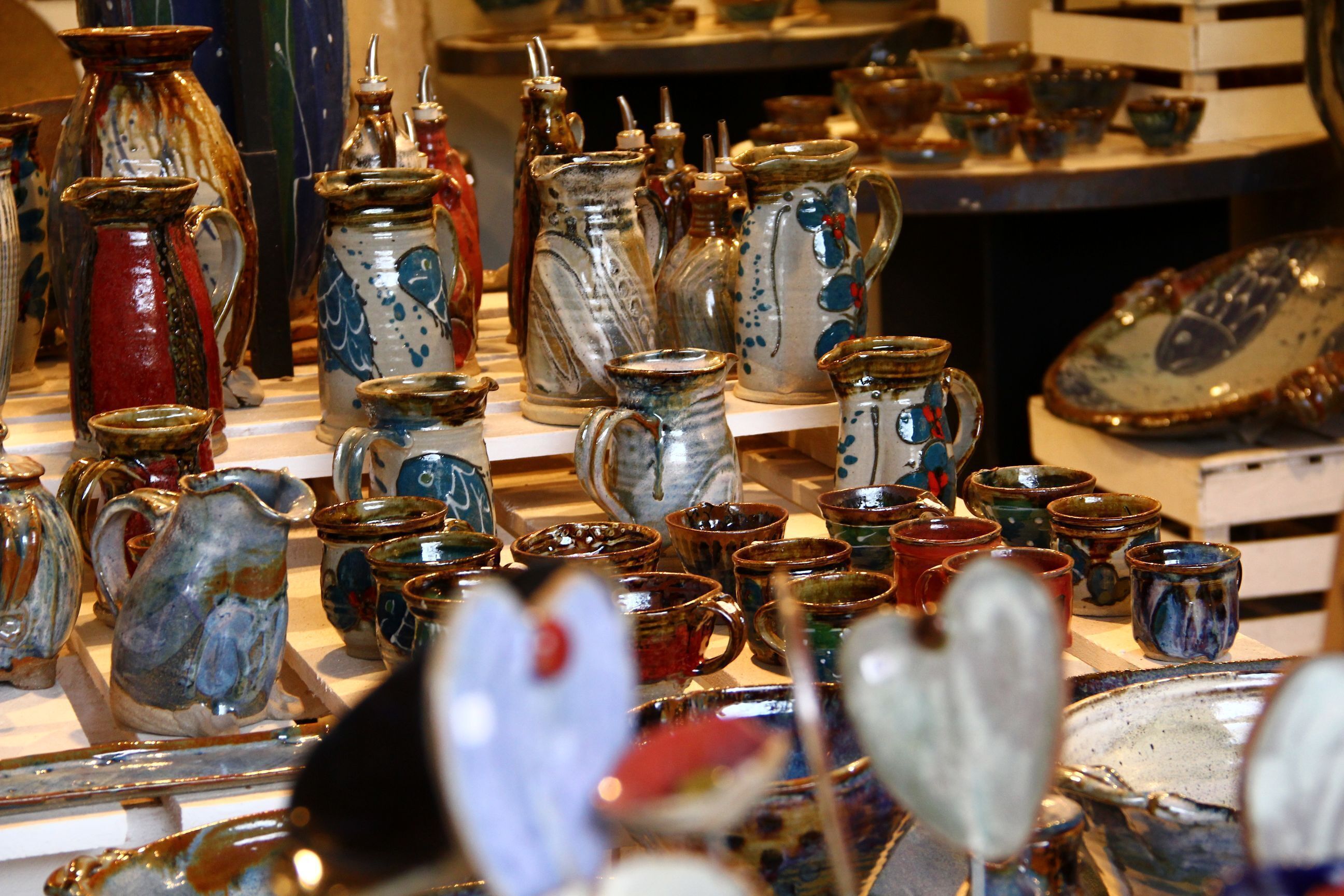 Une variété de tasses et de cruches en céramique sont exposées.
