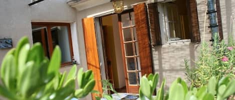 A courtyard with a table, plants, and a door leading to a room.