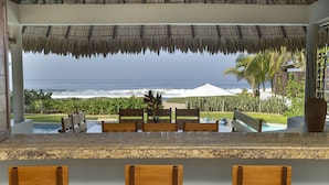 A poolside area with wooden chairs and a view of the ocean. - Private Luxurious Resort Right on the Ocean - Casa De Los Sueños (Puerto Escondido)