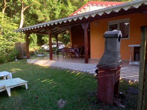 Un patio cubierto con una mesa, sillas, una parrilla y un banco blanco.