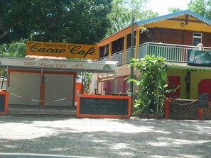 Un restaurante llamado 'Cacao Cafe' con un letrero, un menú en una pizarra y una reja cerrada con candado.