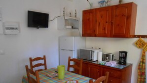A small kitchen with a microwave, toaster, and coffee maker on the counter. There is a table with chairs and a checkered tablecloth. - 2 min from the beach warm welcome in this flowered and wooded park (deshaies)