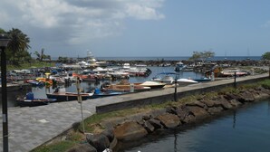 A marina with various boats docked, a concrete walkway, and a rocky shoreline. - 2 min from the beach warm welcome in this flowered and wooded park (deshaies)