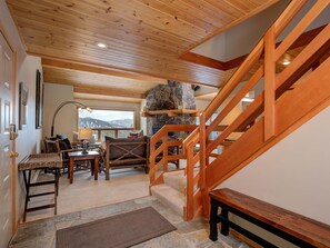 A wooden staircase leading to a stone fireplace with a view of mountains.