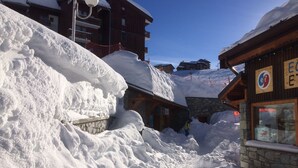 Un pueblo cubierto de nieve en la montaña, con edificios de madera y una construcción de piedra.