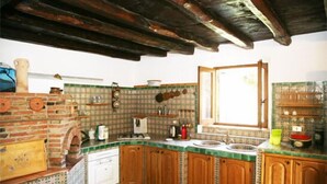 A kitchen with wooden cabinets, a brick oven, and a tiled backsplash.