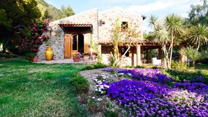 A stone house with a tiled roof, a wooden door, and a covered porch.