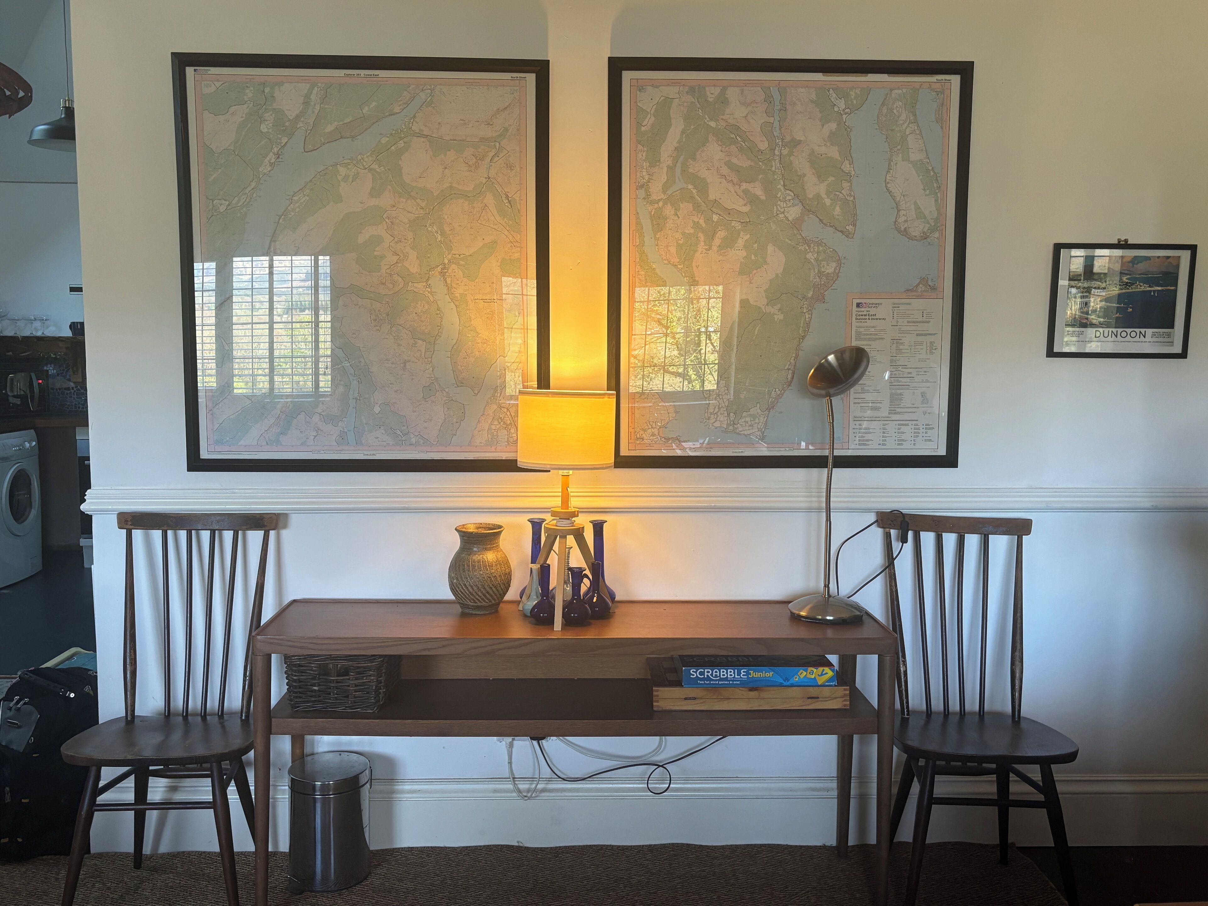 A room with a desk, two chairs, a map, a lamp, and a Scrabble box.