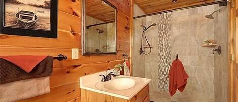 Un baño de cabaña de madera con lavabo, espejo y ducha.