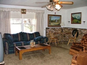 Relax in this inviting living room with a sofa, coffee table, and fireplace, surrounded by a brick accent wall and a ceiling fan.