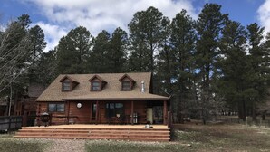 A wooden cabin with a porch, multiple windows, and a chimney. - Family Friendly Lakefront Cedar Log Cabin on 2 acres at Rainbow Lake. (Lakeside)