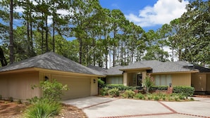 A two-story residential building with a garage, a covered driveway, and a well-maintained lawn. - Pet Friendly Home w/ Free Tennis & Screened Porch (Hilton Head Island)