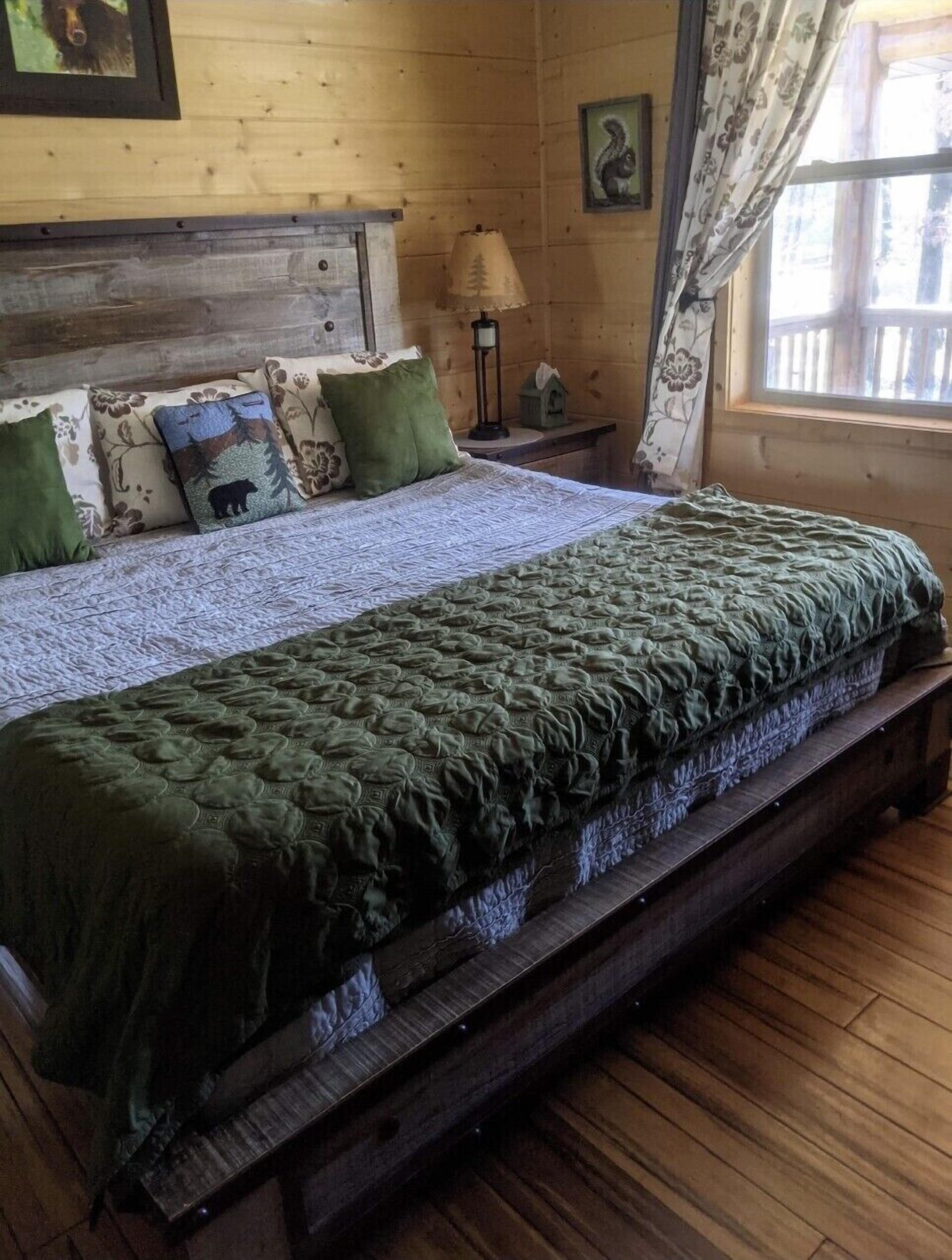 Una cama de madera con una manta verde, un cabecero con diseño de oso y una lámpara en una mesita de noche.