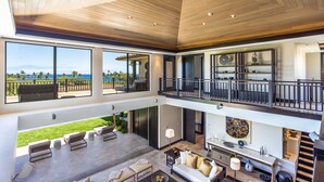 A spacious, multi-level living area with large windows offering ocean views, a balcony, and a modern kitchen.
