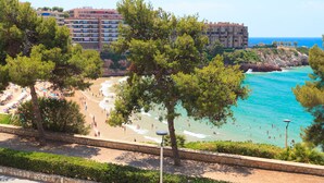 A beach with people, a stone wall, and a building in the background. - Spacious apartment with sea views and pool - UHC MARINA MAR (Salou)