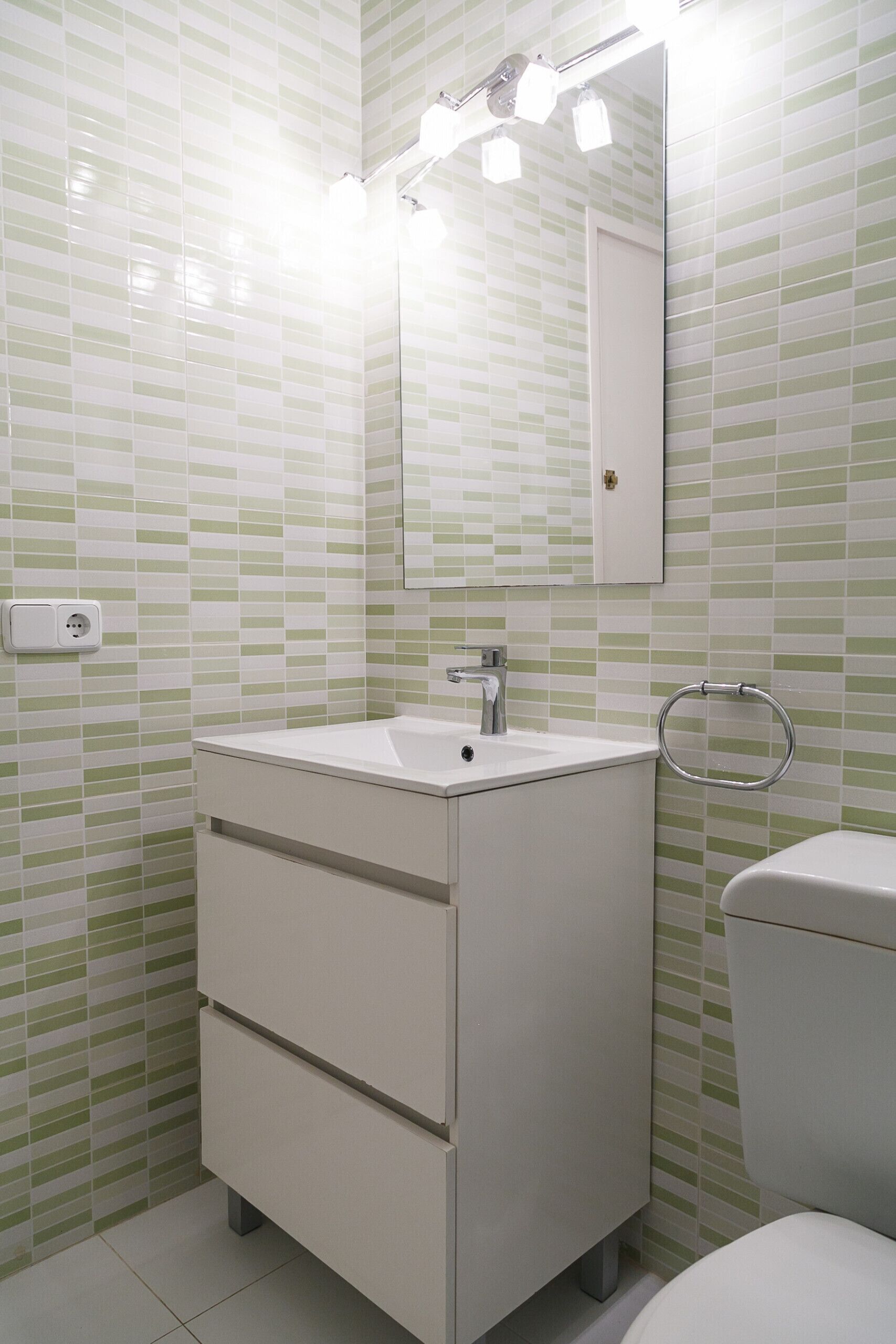 A bathroom with a white sink, mirror, and toilet.