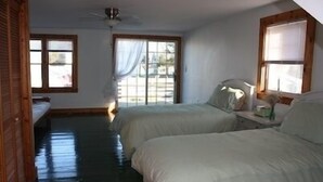 A room with two beds, a ceiling fan, and large windows with curtains. - Amazing Falmouth Heights House Just Steps Away from Beach (Falmouth)