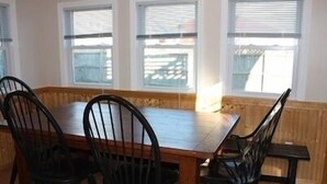 A dining area with a wooden table and four black chairs. - Amazing Falmouth Heights House Just Steps Away from Beach (Falmouth)