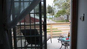 A view through a glass door to an outdoor patio area with a table and chairs. - Amazing Falmouth Heights House Just Steps Away from Beach (Falmouth)