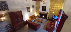 Ein gemütliches Wohnzimmer mit Kamin, einer Couch, einem Couchtisch und einem Fernseher.