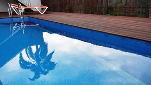 Una piscina con cubierta de madera y escalera metálica.