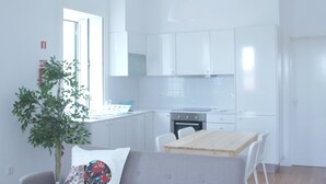 Una sala de estar moderna con un sofá gris, una mesa de comedor de madera y una lámpara colgante.
