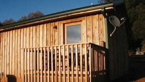 Eine Holzhütte mit Balkon, Satellitenschüssel und Fenster.