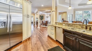 A spacious kitchen with stainless steel appliances, a granite countertop, and a large window providing natural light.