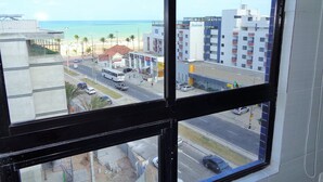 Vista desde una ventana sobre una calle con playa y edificios.