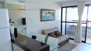 Una cocina moderna con una mesa de comedor de vidrio, un sofá con cojines estampados y un amplio ventanal con vistas al exterior.