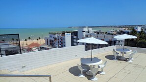 Una terraza en la azotea con mobiliario exterior y vista a la playa.