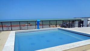 Una piscina en la azotea con vistas despejadas al océano y una playa al fondo.