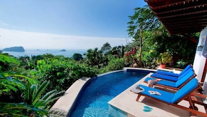 A private pool with blue lounge chairs and a view of the ocean.