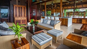 A spacious outdoor lounge area with wicker furniture, a central coffee table, and a seating arrangement around a bar area.